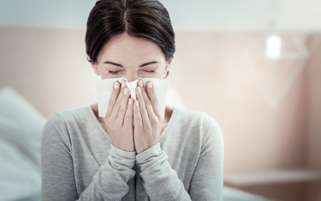 sneezing lady sneezing into tissue due to allergies